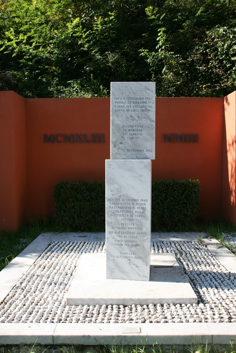 Monumento a Montolli, commemorazione di eventi storici con stele centrale e decorazioni floreali.