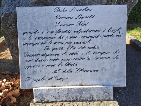 Monumento commemorativo a Barachini, Barsotti e Selmi, con iscrizioni su una pietra e contesto naturale circostante.