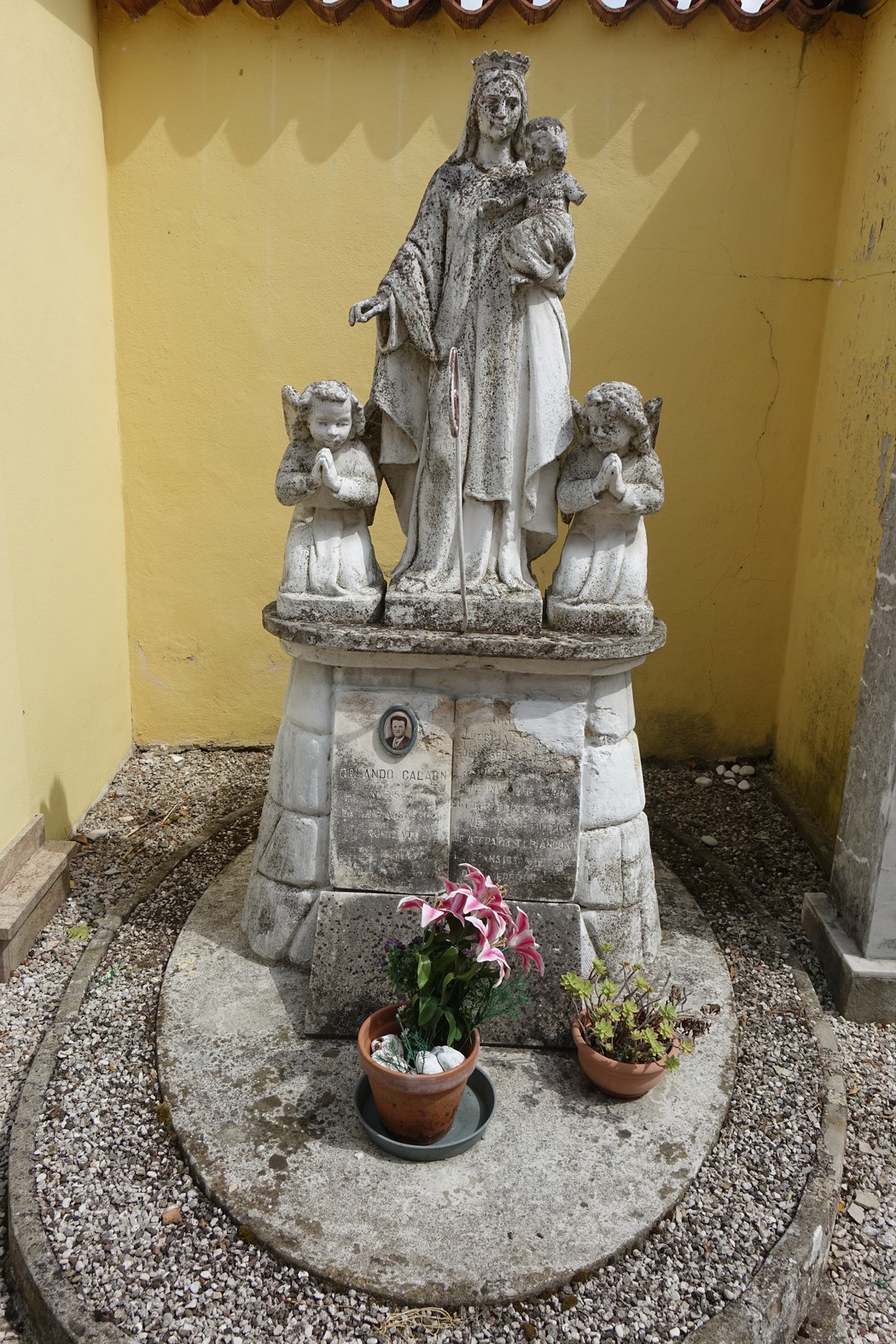 Sepolcro di Calaon, con statua della Madonna e fiori, incarna la tradizione e la memoria storica del luogo.