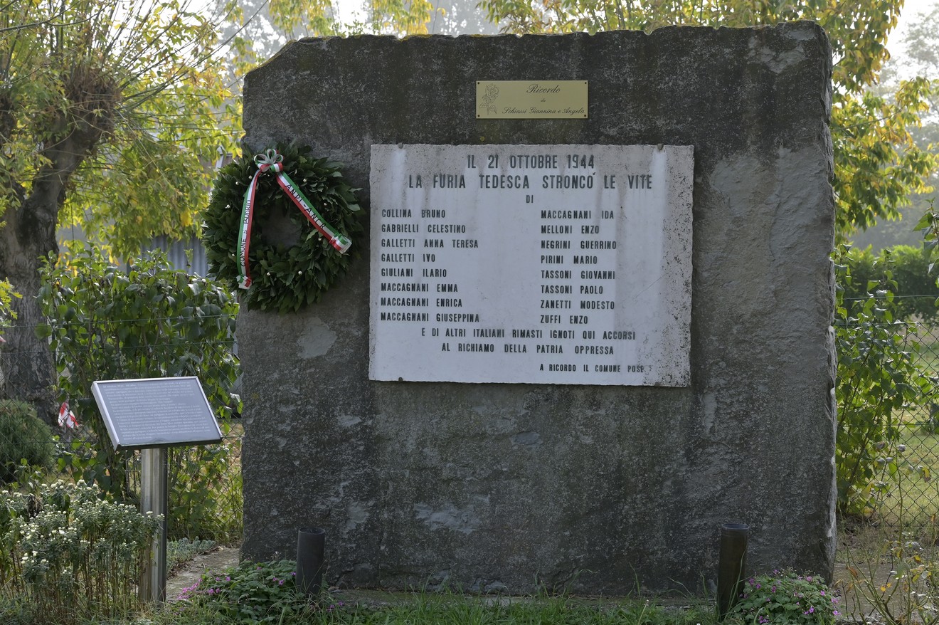 Monumento commemorativo con lapide dedicata alle vittime della Strage di Vigorso, decorato con una corona d'alloro.