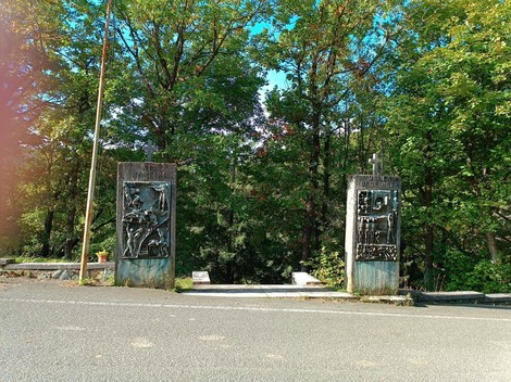 Memoriale dei caduti della Benedicta, con pannelli in rilievo circondati da alberi. Un luogo di commemorazione.