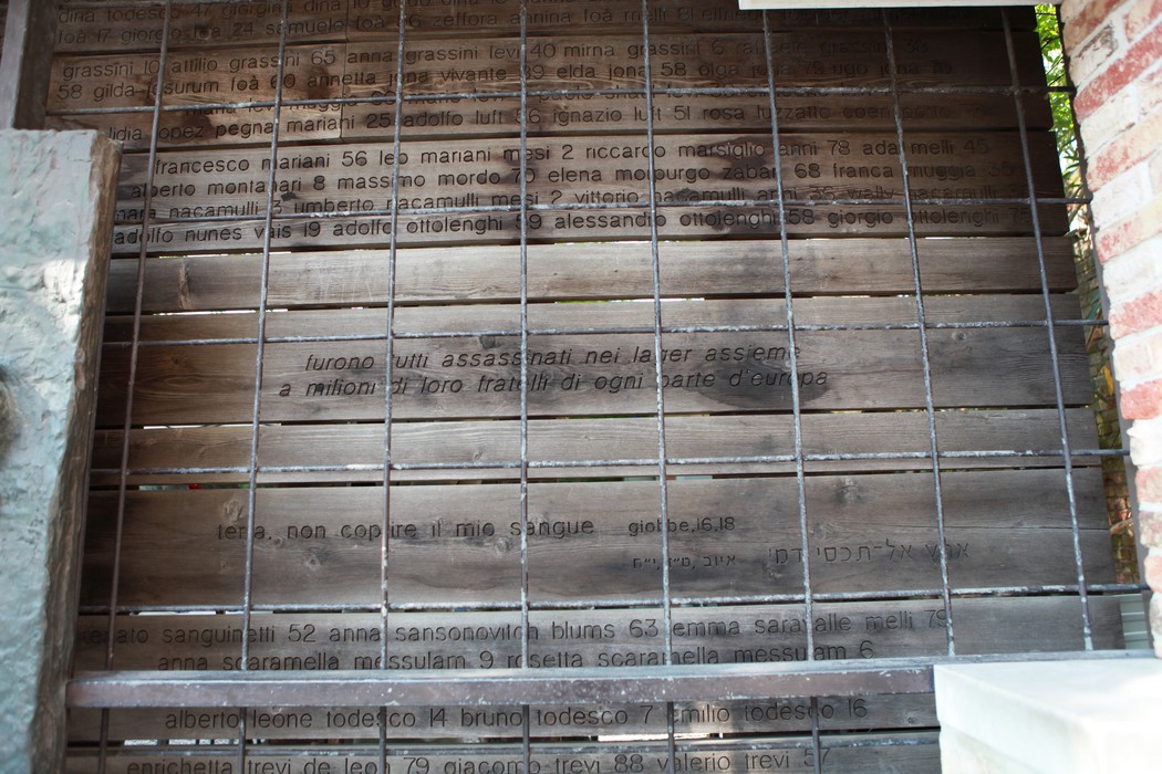 Immagine di una superficie di legno con iscrizioni che ricordano eventi o persone legate a "L'ultimo treno".