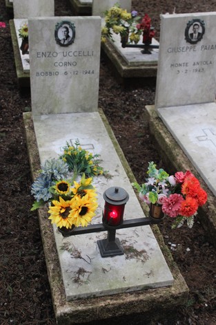 Tombe perpetue dei caduti per la Libertà, decorate con fiori colorati e lume acceso.