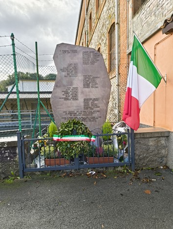 Monumento commemorativo dedicato agli uccisi della Botte di Pioppe, con bandiera italiana e decorazioni floreali.