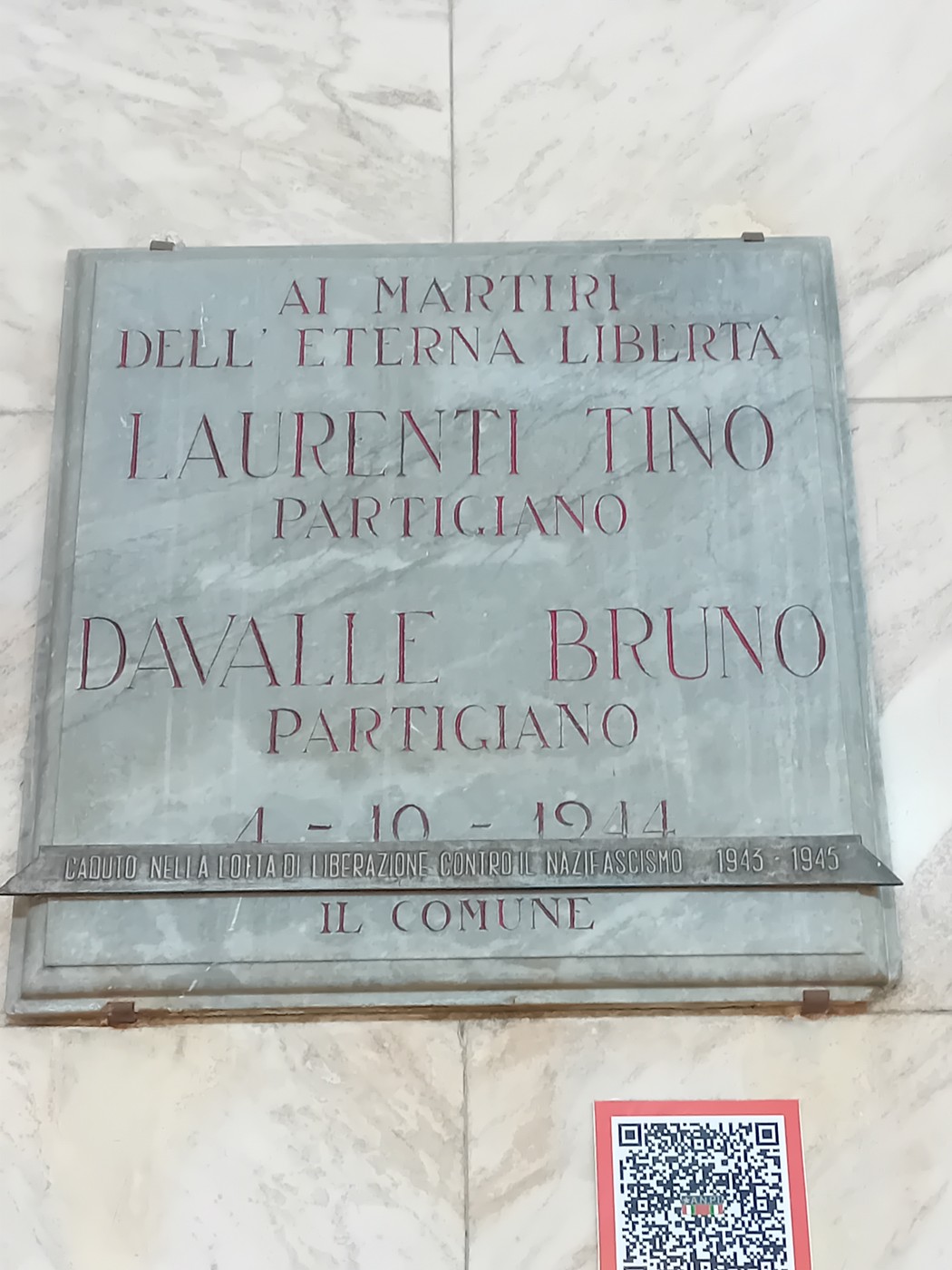 Lapide commemorativa in marmo dedicata ai partigiani Laurenti e Davalle, con iscrizione in rosso e nero.