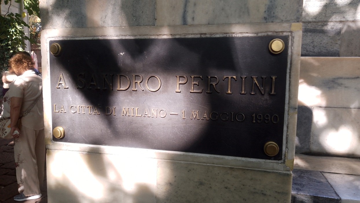 Targa metallica con iscrizione fissata a un monumento in pietra.