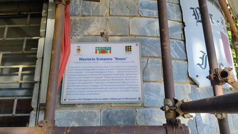 Targa commemorativa di Maciocio, con informazioni storiche su Ermanno "Rosso" e il contesto locale.