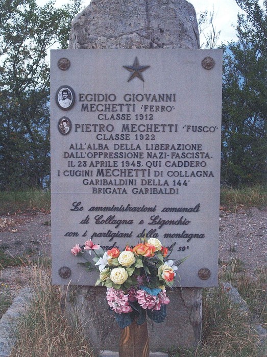 Cippo commemorativo dedicato ai Mechetti, eroi della Resistenza, con omaggio floreale ai loro sacrifici.