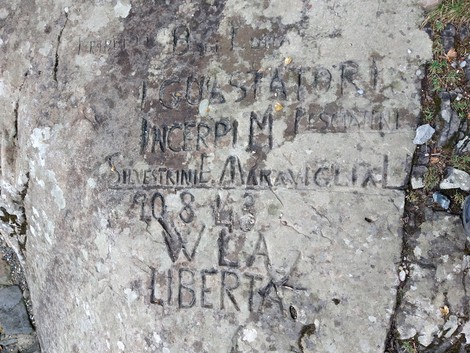 Scritta partigiana incisa su una roccia al Lago Santo, simbolo di lotta per la libertà e la resistenza.