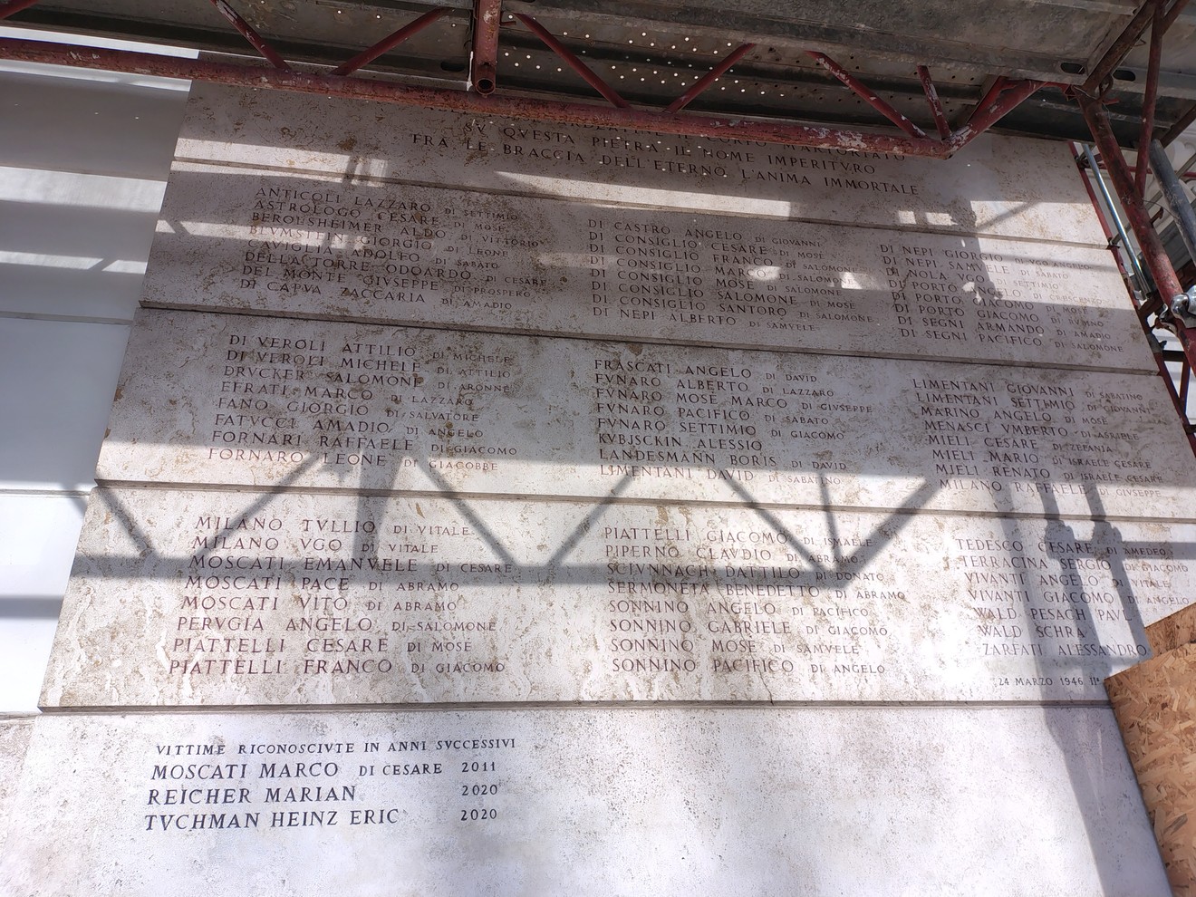 Lapide commemorativa con nomi e date, appartenente a una sinagoga, visibilmente in corso di restauro.