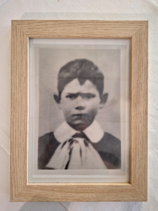 Ritratto in bianco e nero di un giovane ragazzo con espressione seria, incorniciato elegantemente.