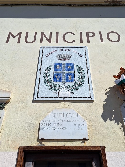 Facciata del municipio con stemma comunale e, sotto, lapide con iscrizione ai caduti civili.