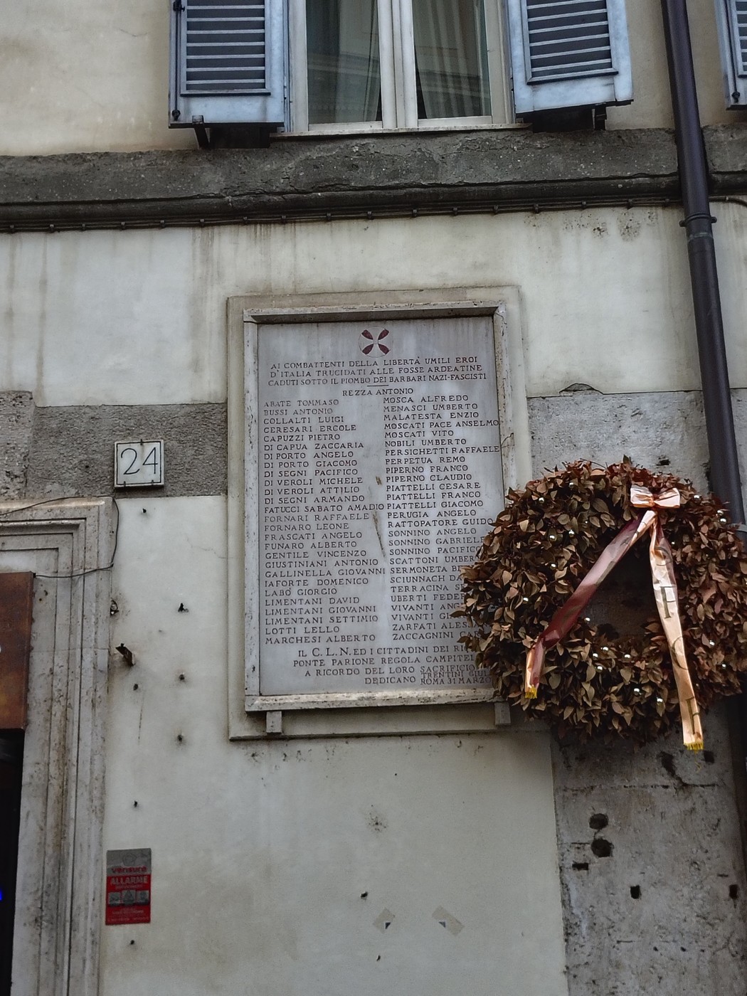 Lapide commemorativa dedicata ai caduti dei rioni Ponte, Parione, Regola e Campitelli, affissa su un muro.