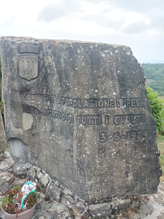 Monumento ai caduti, realizzato in pietra, con iscrizioni commemorative e vista panoramica sul paesaggio circostante.