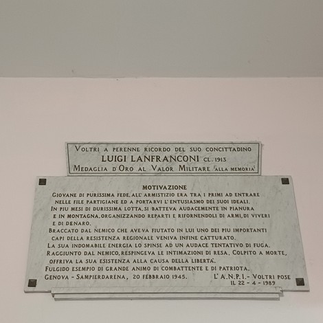 Due targhe in marmo affisse a una parete chiara, con iscrizioni dedicate a Luigi Lanfranconi.