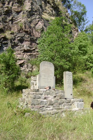 Monumento ai partigiani e a Siligato, situato tra la vegetazione su un basamento di pietra.