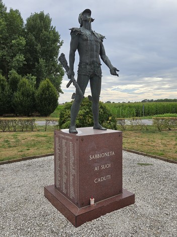 Monumento ai Caduti di Sabbioneta, raffigurante un guerriero in posizione eretta, circondato da un'area verde.