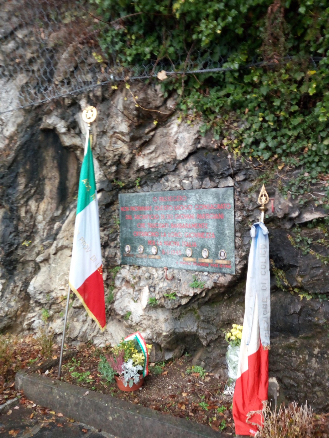 Lapide commemorativa della strage della Montagnetta di Fiumelatte con bandiere e fiori.
