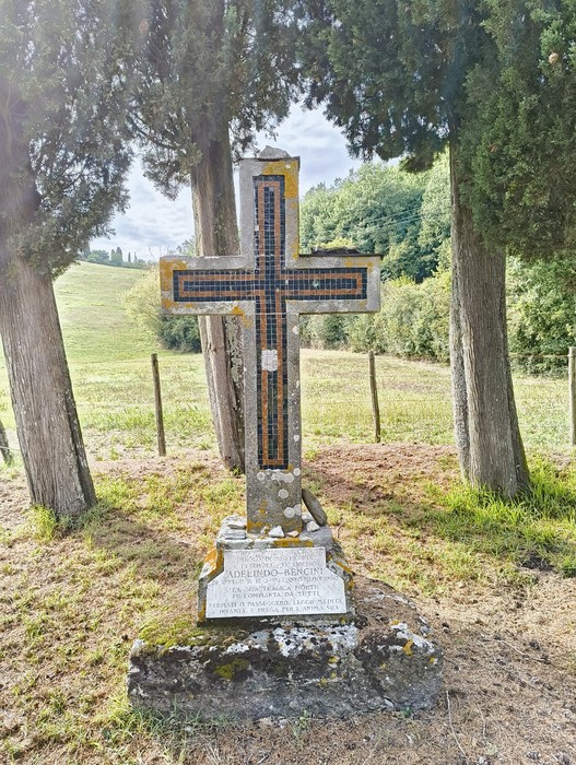 Croce storica di Bencini immersa nel verde, circondata da alberi e panorami naturali.