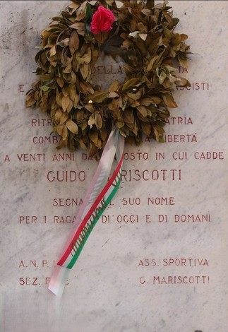 Lapide commemorativa con corona di alloro e fiore, dedicata a Guido Mariscotti, simbolo di libertà e sacrificio.