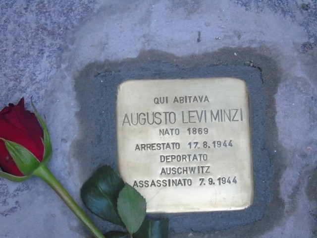 Pietra d'inciampo dedicata a Augusto Levi Minzi, con rosa rossa accanto, commemorando la sua tragica storia.