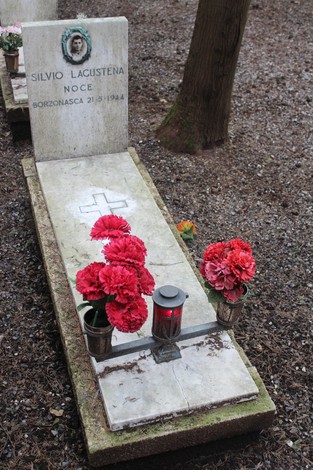 Tomba decorata con fiori rossi, commemorando i caduti per la Libertà in un cimitero.