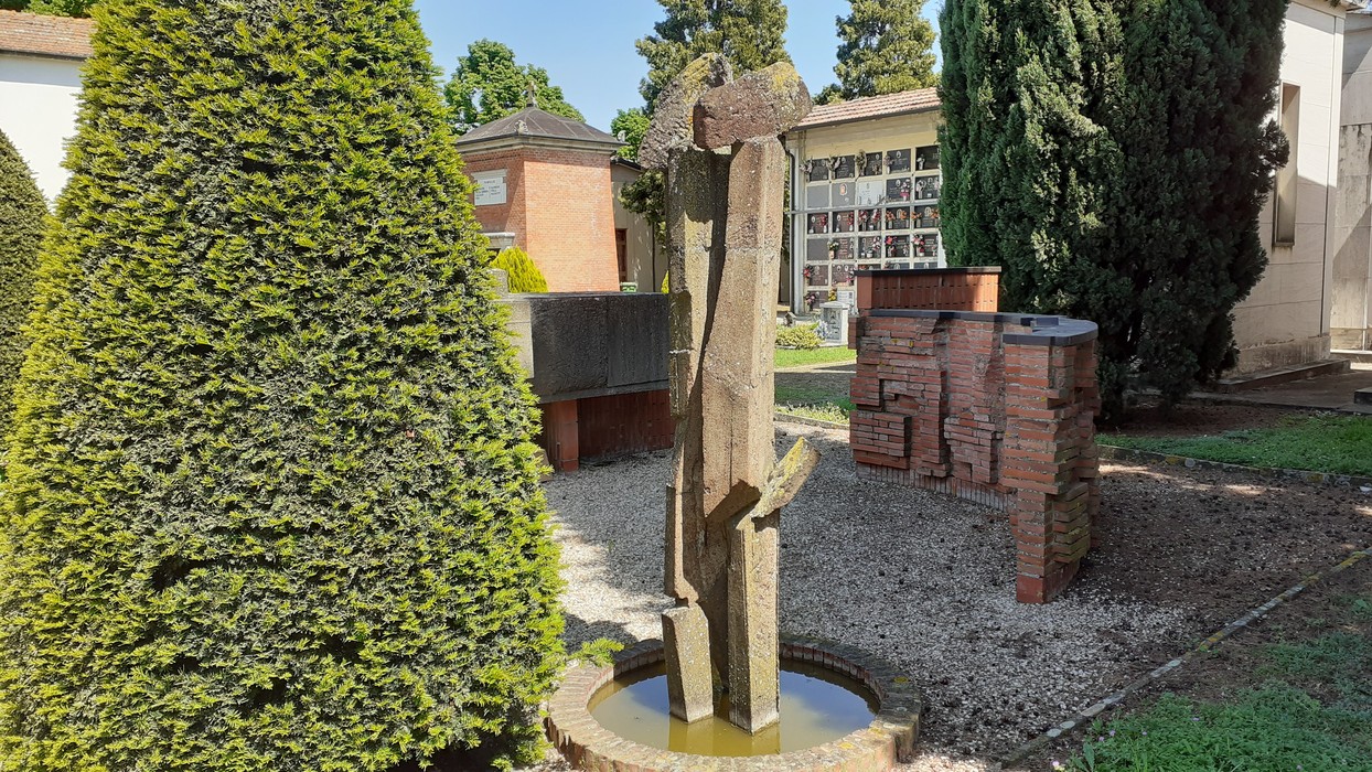 Sepolcro di Cassani, commemorativo, situato tra eleganti alberi e strutture funerarie. Atmosfera di rispetto e tranquillità.