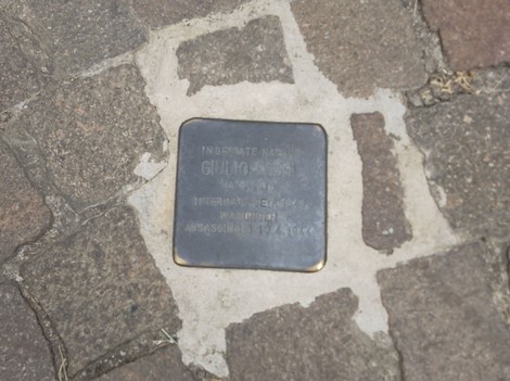 Pietra d'inciampo commemorativa su un pavimento di pietra, dedicata a una vittima del regime nazista.