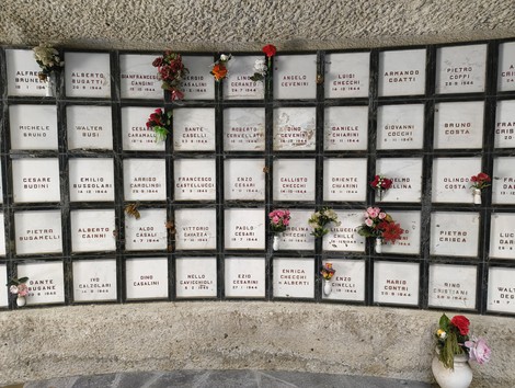 Monumento Ossario dedicato ai caduti partigiani, con registri e fiori commemorativi.