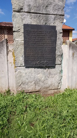 Monumento ai combattenti per la Libertà, in pietra con iscrizioni commemorative, circondato da verde.