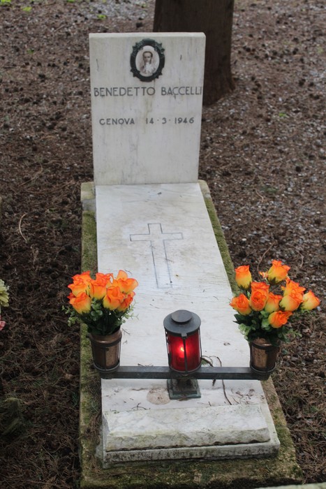 Tomba con lapide di Benedetto Baccelli decorata con fiori arancioni e una lampada rosso.