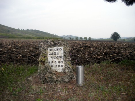 Cippo commemorativo a Soressi in memoria di un partigiano, situato in un'area rurale.