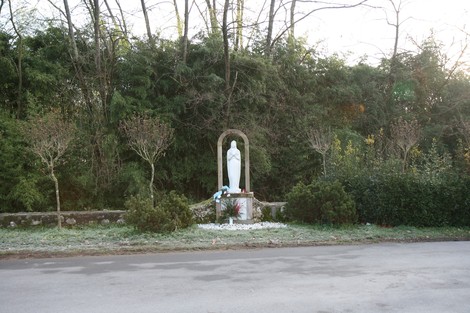 Monumento al cimitero di San Martino, immerso nel verde, con statua e aiuole curate.