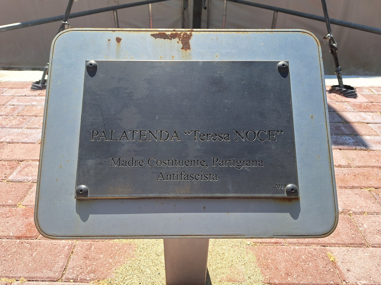 Targa commemorativa dedicata a Teresa Noce, madre costituente e partigiana antifascista, su base in pietra.