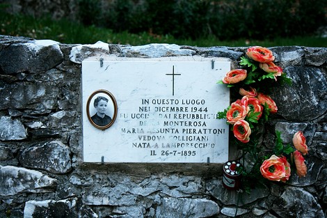 Lapide commemorativa a Pierattoni, in memoria della vittima della Seconda Guerra Mondiale; fiori decorativi sul lato.