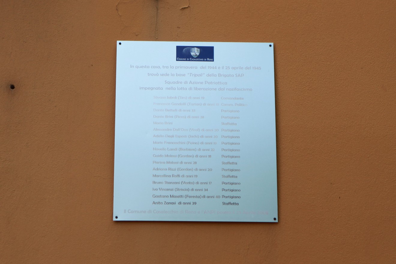 Targa commemorativa dedicata ai partigiani della SAP, affissa su un muro, con elenco di nomi e date significative.