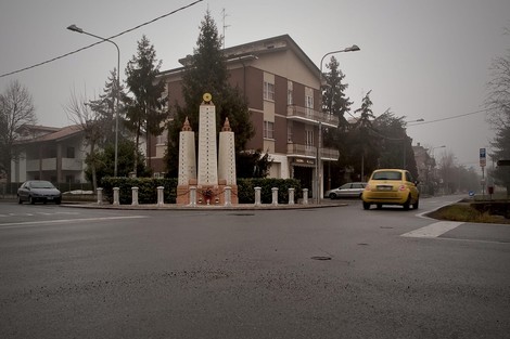 Monumento ai caduti di Migliarina, situato in una rotonda, immerso in un'atmosfera nebbiosa.