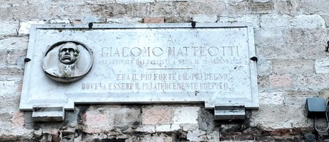 Lapide commemorativa a Giacomo Matteotti, situata su una parete, con un incise e un rilievo.