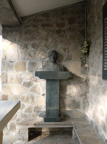 Busto commemorativo in pietra, situato all'interno del Sacrario di Ca' Marastoni, in un ambiente rustico.