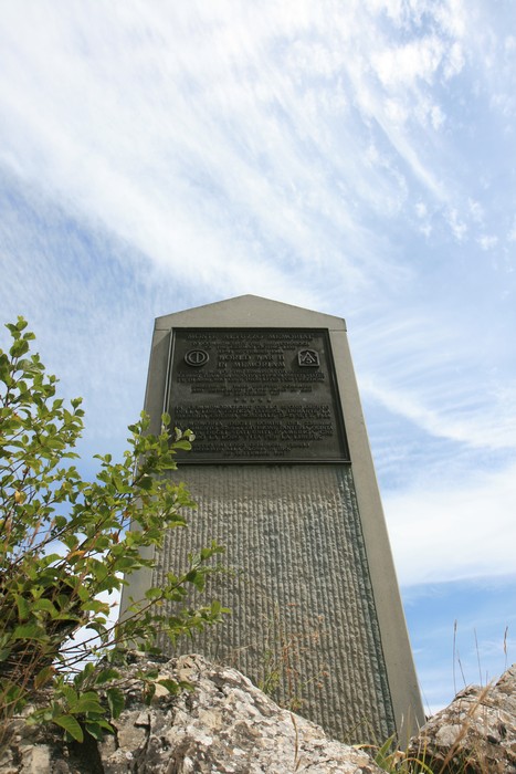 Cippo commemorativo della Battaglia del Monte Altuzzo, immerso in un paesaggio naturale.