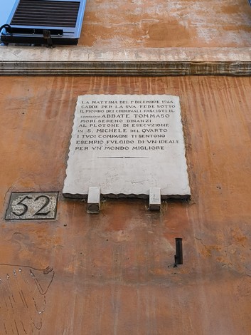 Lapide commemorativa dedicata all'Abbate Tommaso, situata su una parete di un edificio.