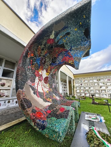Monumento contemporaneo ai martiri della Creda, caratterizzato da colori vivaci e forme astratte, in un contesto di memoria.