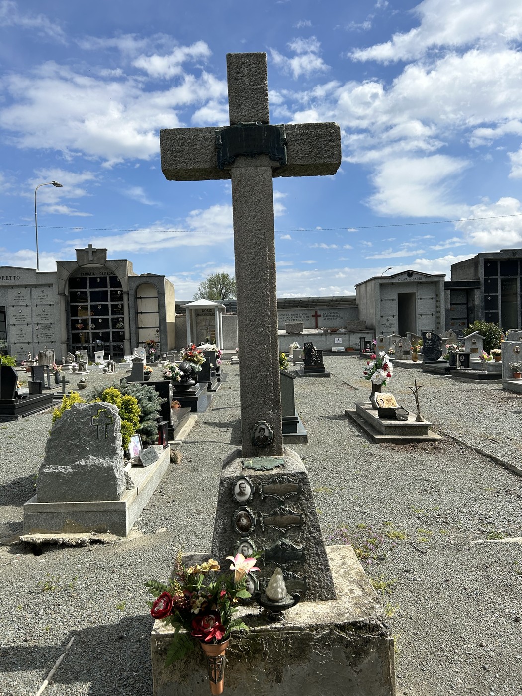 Croce in memoria degli internati militari, collocata in un cimitero. Decorazioni floreali ai suoi piedi.