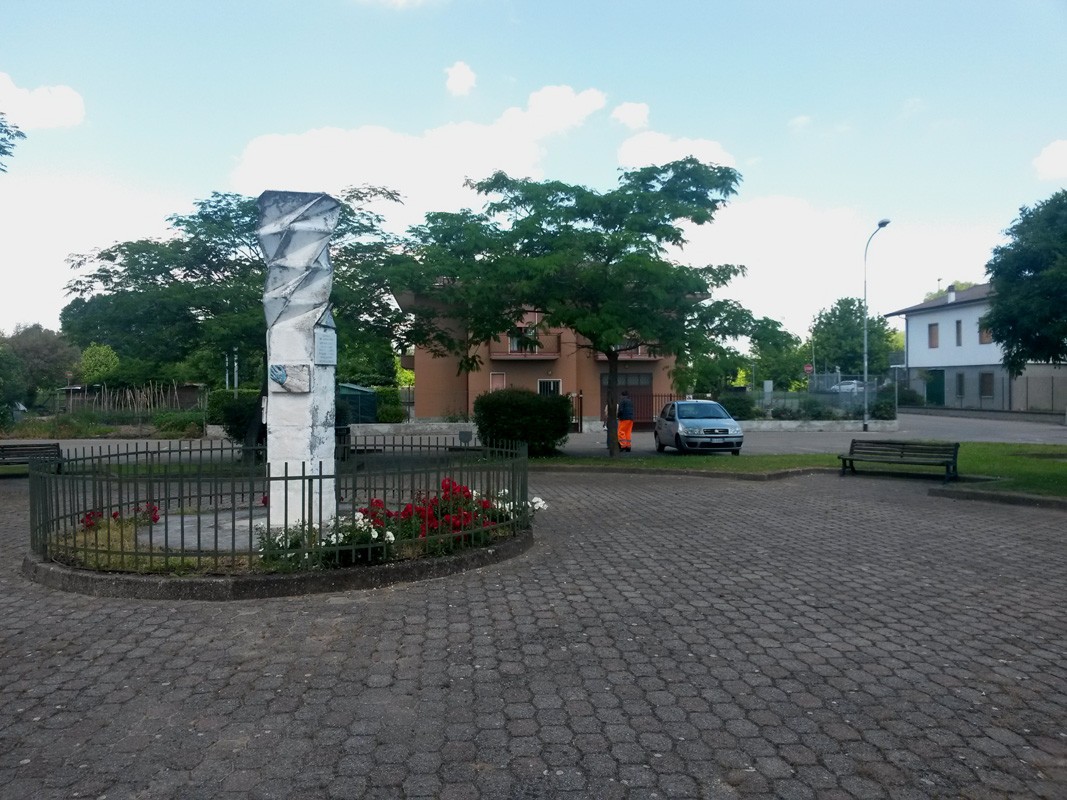 Monumento ai caduti della Resistenza di Lardirago, situato in un'area verde con panchine e fiori.