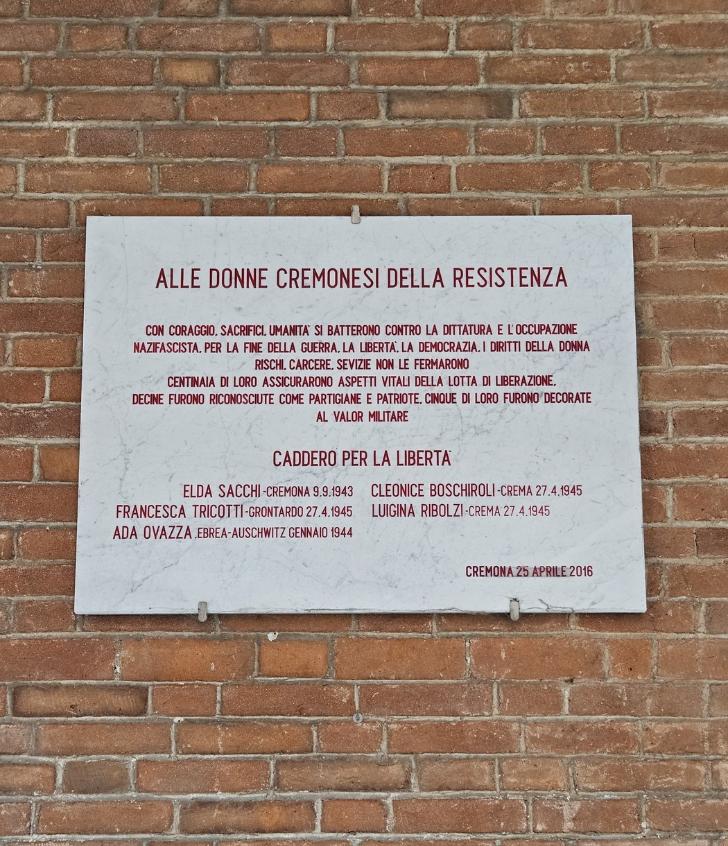Lapide dedicata alle donne cremonesi della Resistenza, commemorativa e suggestiva, su muro di mattoni.