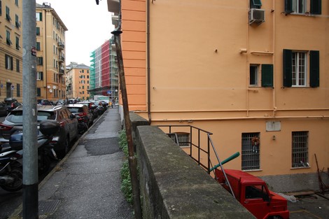 Veduta di una strada a Lucarno con edifici colorati, auto parcheggiate e un muro in primo piano.