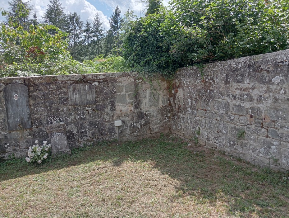 Vista della "Tomba di Ricci" con muretti in pietra e vegetazione circostante in un'area verde.