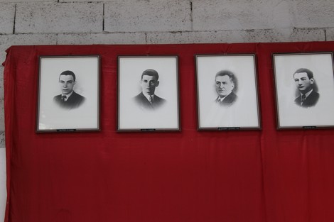 Quattro ritratti in bianco e nero appesi su uno sfondo rosso, commemorano i caduti dell'Ansaldo Elettrotecnico.