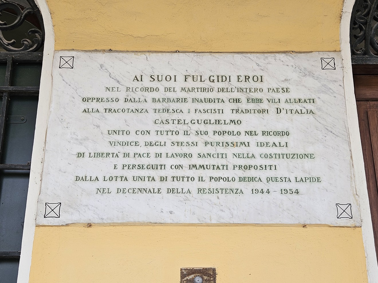 Lapide commemorativa che onora i caduti della Resistenza, con dedica storica e messaggi di libertà.