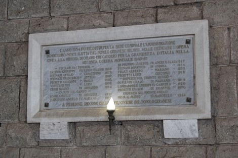 Lapide commemorativa con targa dedicata ai caduti in guerra, incastonata in una parete di pietra.